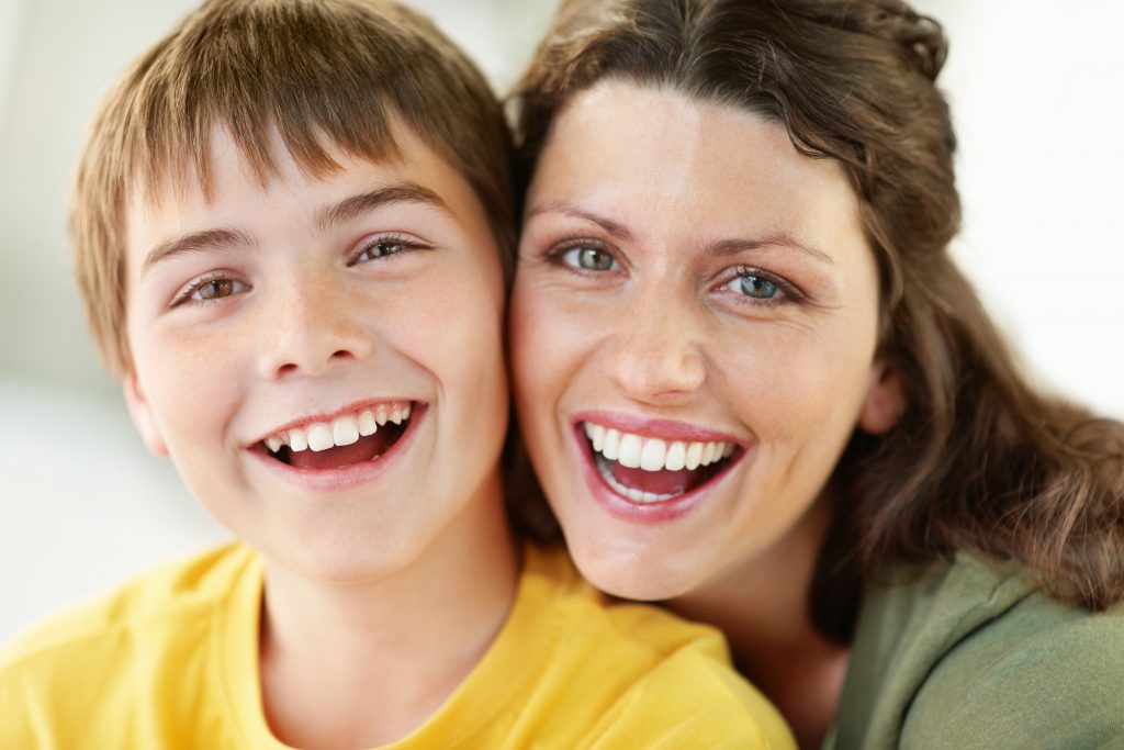 A child and a mature woman smiling together