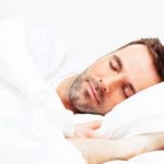 Young man sleeping in white bedding