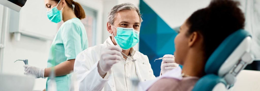 dentist with face mask talking to woman