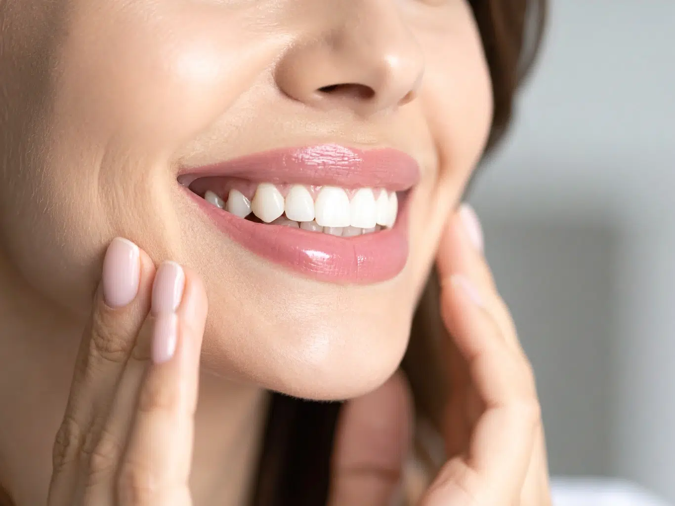 healthy white teeth woman smiling with healthy white teeth and pink glossy lipstick touching face