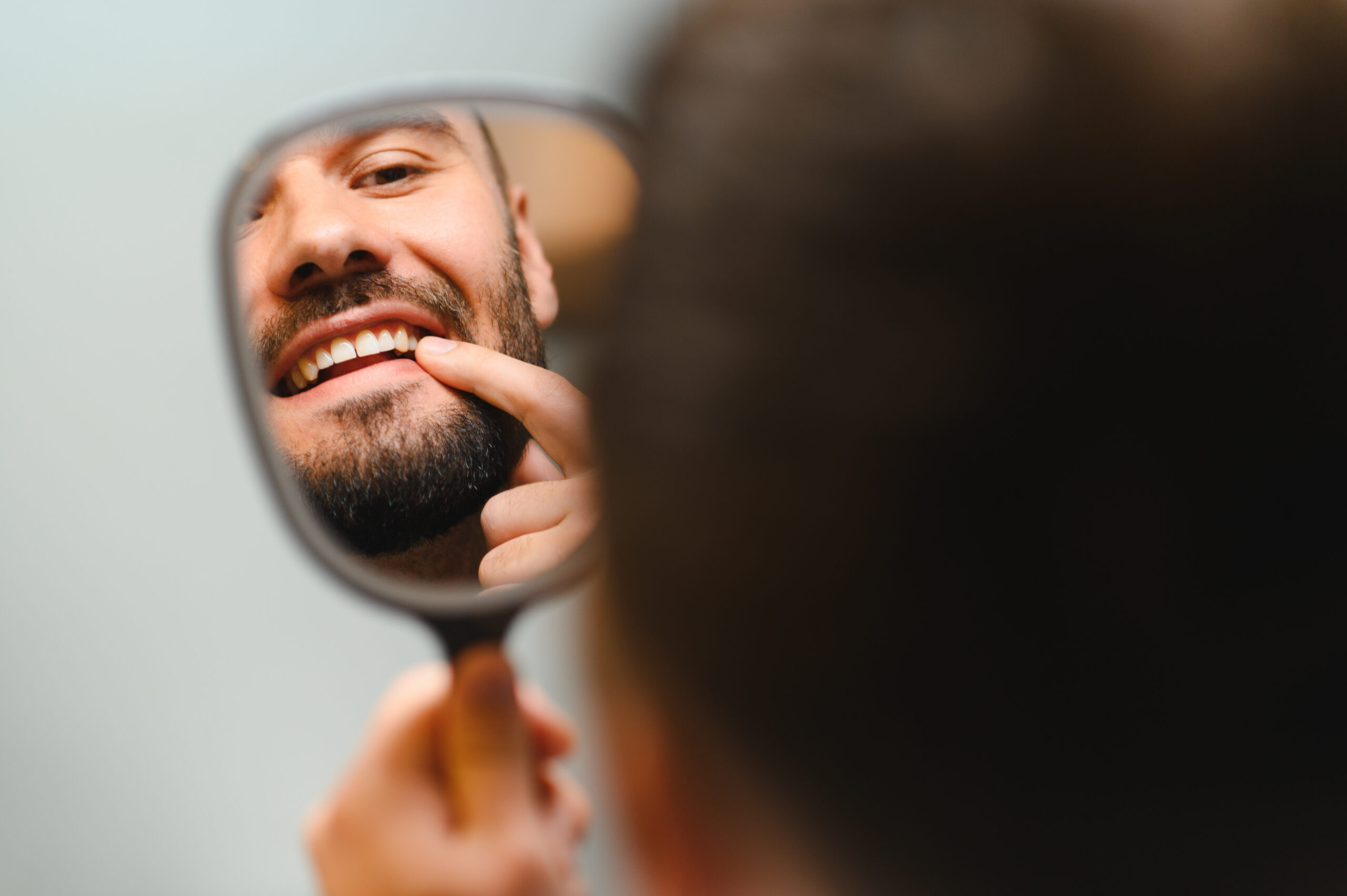 Man checking oral health looking in mirror invisalign dos donts scaled